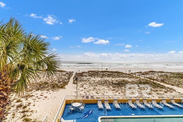 exterior space with a swimming pool, a water view, and a beach view