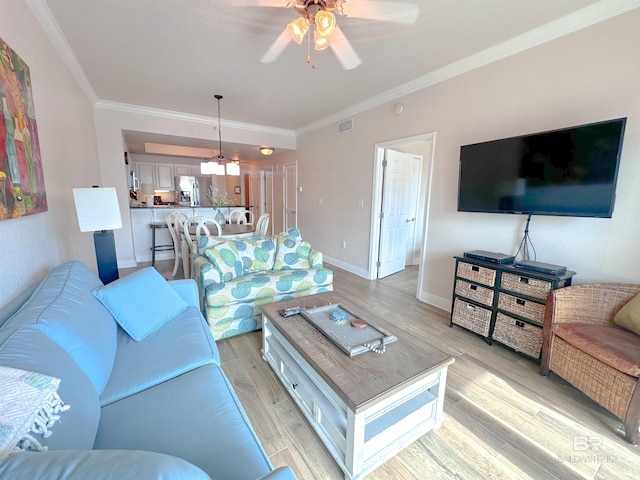 living room featuring ceiling fan with notable chandelier, light hardwood / wood-style floors, and crown molding