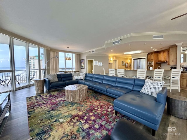 living room with dark hardwood / wood-style flooring, crown molding, and a wealth of natural light