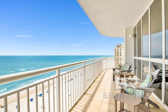 balcony featuring a view of the beach and a water view