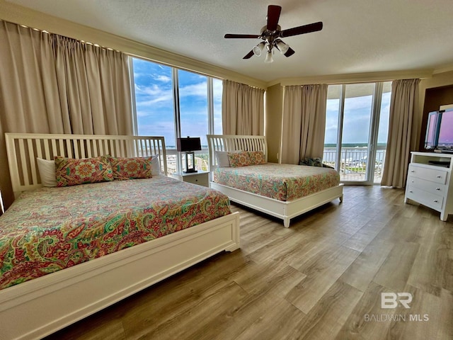 bedroom with ceiling fan, hardwood / wood-style floors, a textured ceiling, and access to exterior