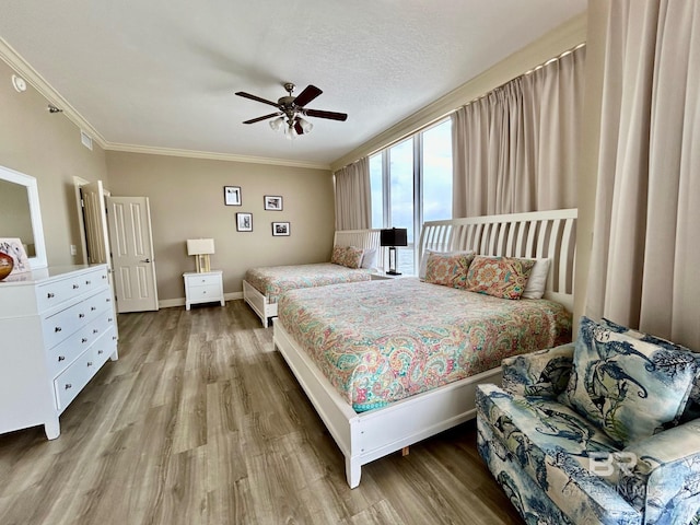 bedroom with light wood-type flooring, ceiling fan, crown molding, and a textured ceiling