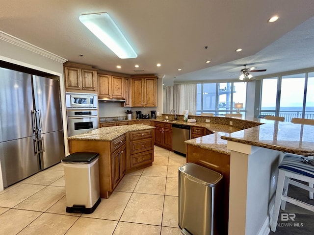 kitchen with sink, a water view, a kitchen bar, a spacious island, and appliances with stainless steel finishes