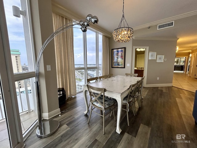 dining area with a notable chandelier, crown molding, and dark wood-type flooring