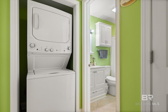 laundry area with a sink, laundry area, stacked washer / dryer, and light tile patterned flooring