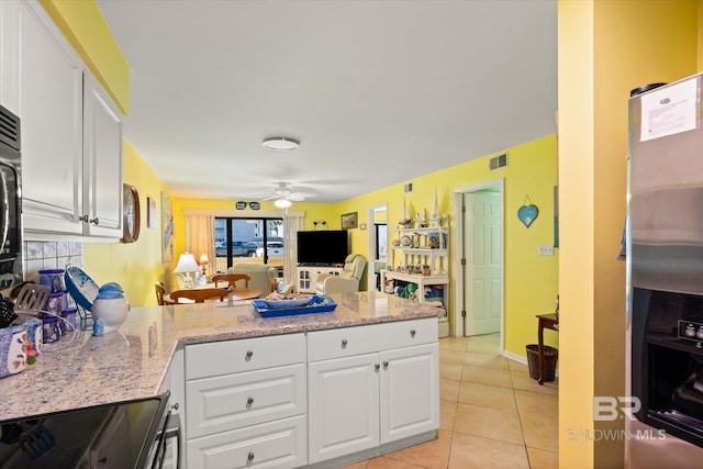 kitchen with open floor plan, appliances with stainless steel finishes, light tile patterned floors, and white cabinets