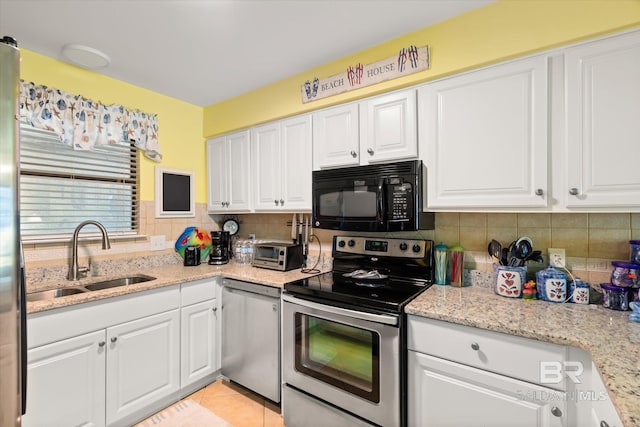 kitchen featuring light stone countertops, appliances with stainless steel finishes, white cabinets, and a sink