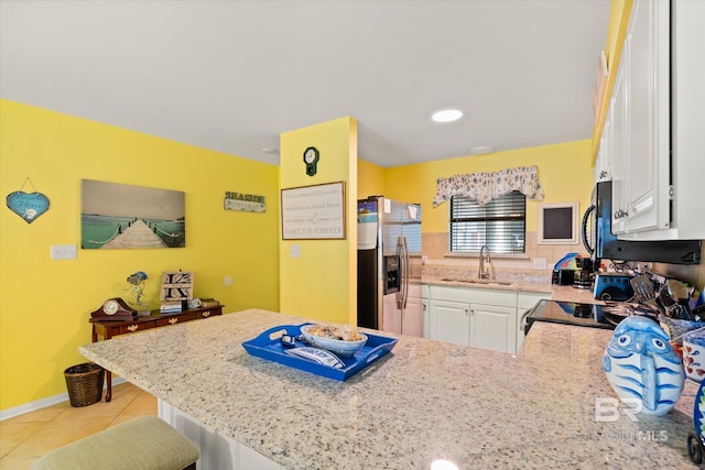 kitchen with white cabinets, a peninsula, stainless steel refrigerator with ice dispenser, and a sink