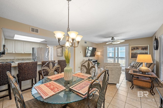 dining space with ceiling fan with notable chandelier, light tile patterned floors, and a textured ceiling