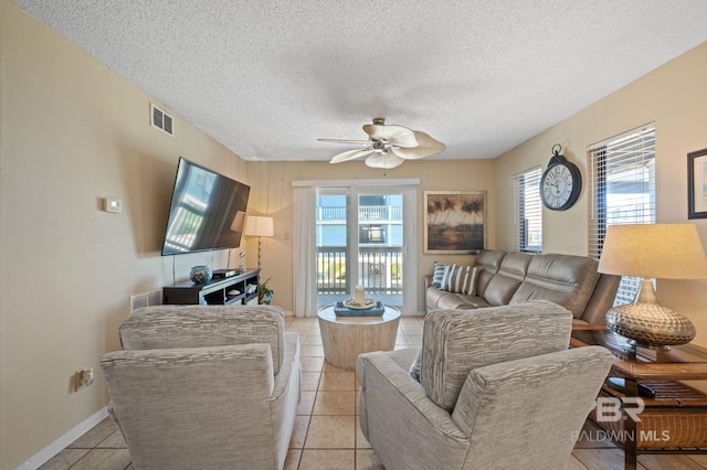 living room with ceiling fan, light tile patterned floors, and a textured ceiling