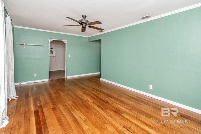 empty room with ceiling fan, crown molding, and wood-type flooring