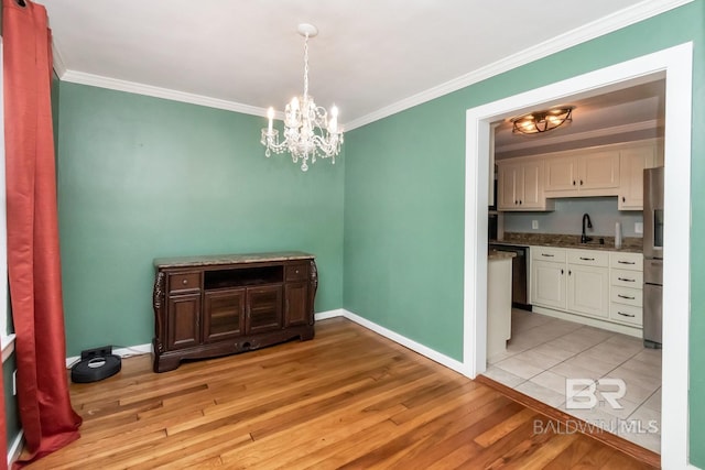 dining room with light wood-type flooring, an inviting chandelier, crown molding, and sink