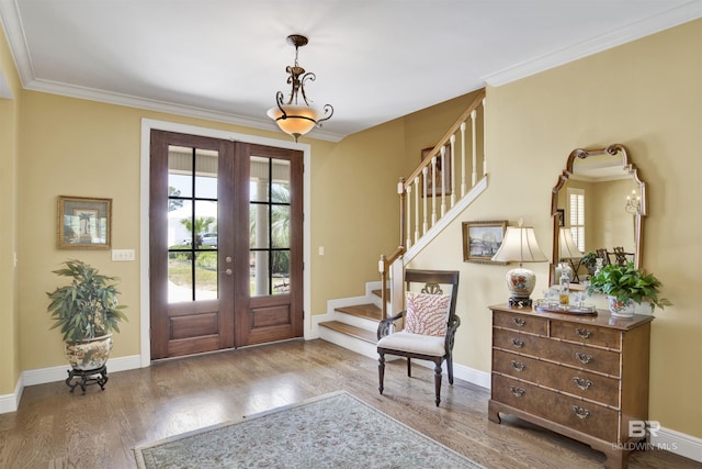 foyer entrance featuring hardwood / wood-style floors, ornamental molding, and french doors