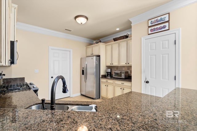 kitchen featuring stainless steel appliances, dark stone countertops, sink, cream cabinets, and crown molding