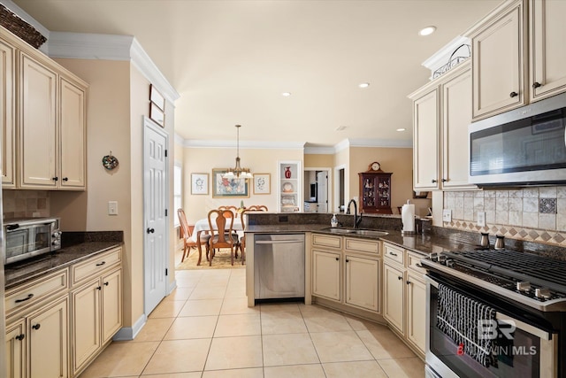 kitchen featuring sink, hanging light fixtures, appliances with stainless steel finishes, light tile patterned floors, and cream cabinets