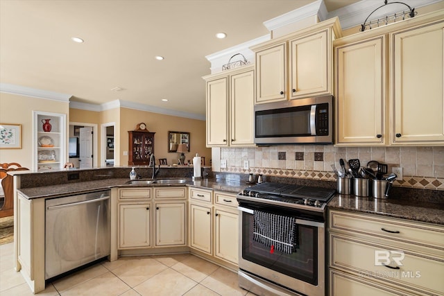 kitchen featuring appliances with stainless steel finishes, cream cabinetry, dark stone counters, and sink