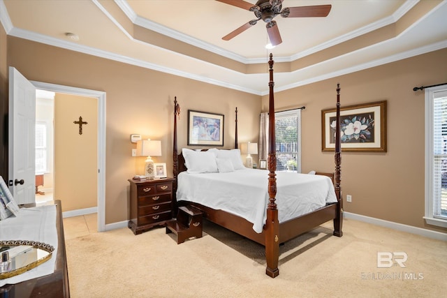 bedroom with ceiling fan, light colored carpet, a tray ceiling, and crown molding