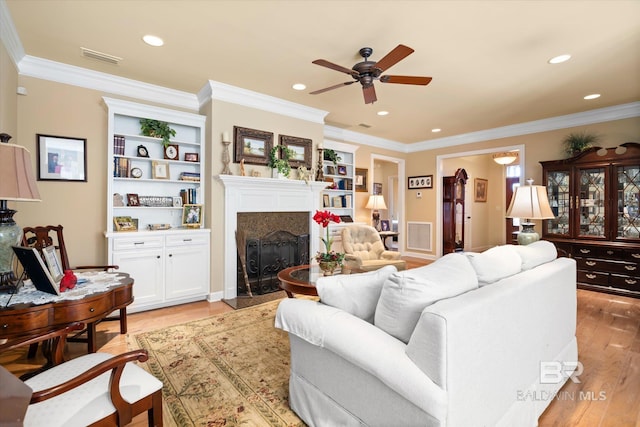 living room with light hardwood / wood-style floors, ceiling fan, built in shelves, and a premium fireplace