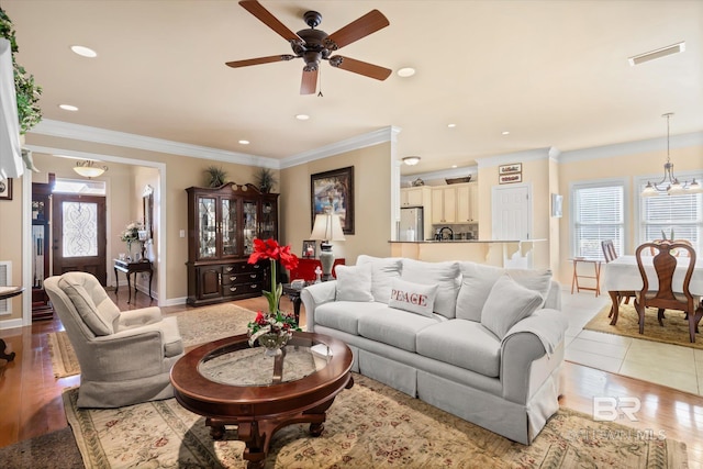 tiled living room with crown molding and ceiling fan with notable chandelier