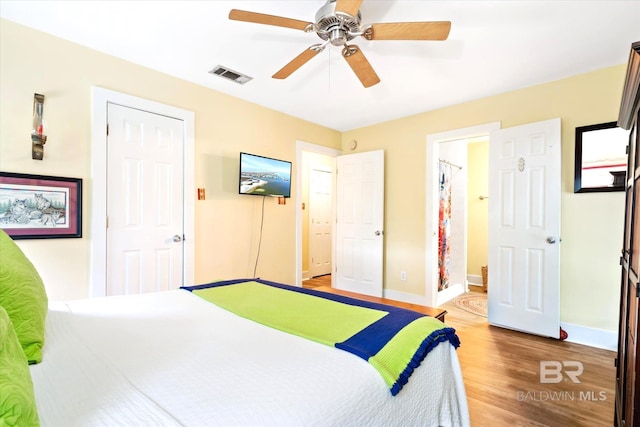 bedroom with light hardwood / wood-style flooring, ceiling fan, and ensuite bathroom