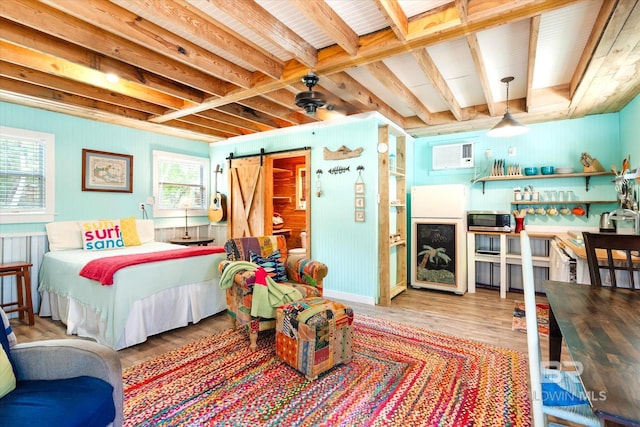 bedroom with beamed ceiling, hardwood / wood-style flooring, and a barn door