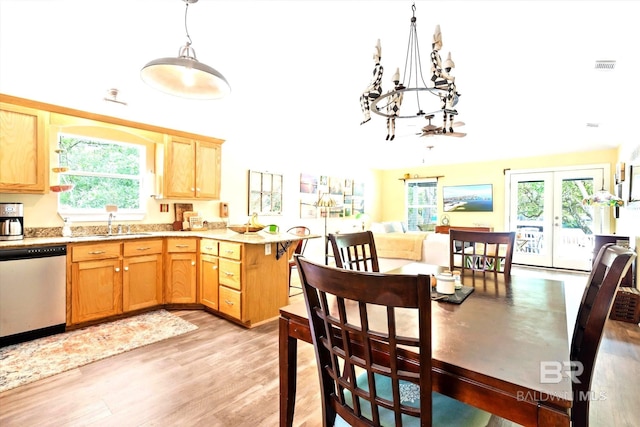 kitchen featuring a healthy amount of sunlight, light hardwood / wood-style floors, an inviting chandelier, and stainless steel dishwasher