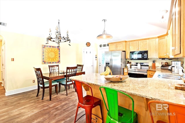 kitchen with decorative light fixtures, light hardwood / wood-style flooring, range with electric stovetop, stainless steel fridge, and sink