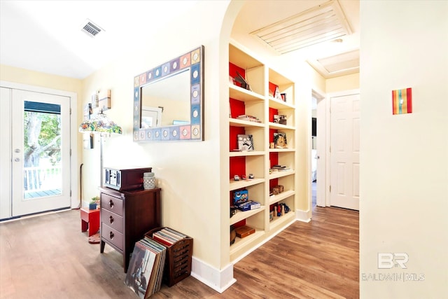 hall featuring wood-type flooring and built in shelves