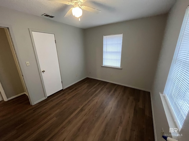 unfurnished bedroom with dark hardwood / wood-style flooring, a textured ceiling, and ceiling fan