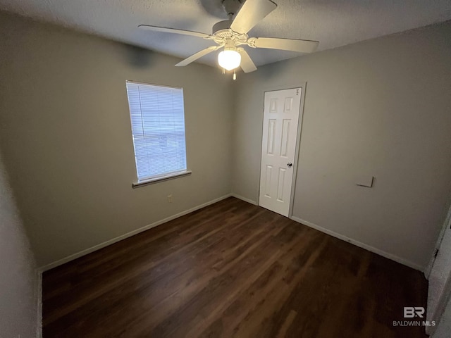 empty room with ceiling fan, dark wood-type flooring, and a textured ceiling