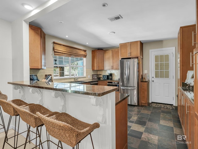 5410 Florida Ave, Orange Beach, AL 36561 - kitchen featuring freestanding refrigerator, tasteful backsplash, a peninsula, brown cabinets, and visible vents
