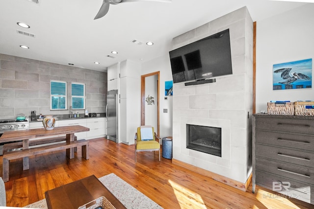 living room with light wood-style floors, recessed lighting, visible vents, and a fireplace