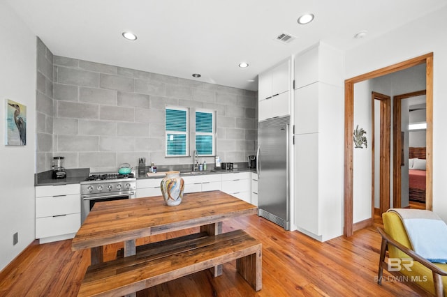 kitchen with high end appliances, visible vents, a sink, and modern cabinets