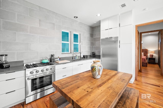 kitchen with stainless steel appliances, visible vents, white cabinets, a sink, and modern cabinets