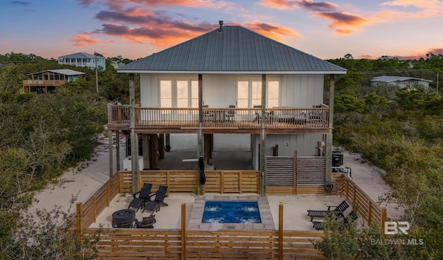 back of property at dusk with an outdoor pool, metal roof, stairway, and a patio