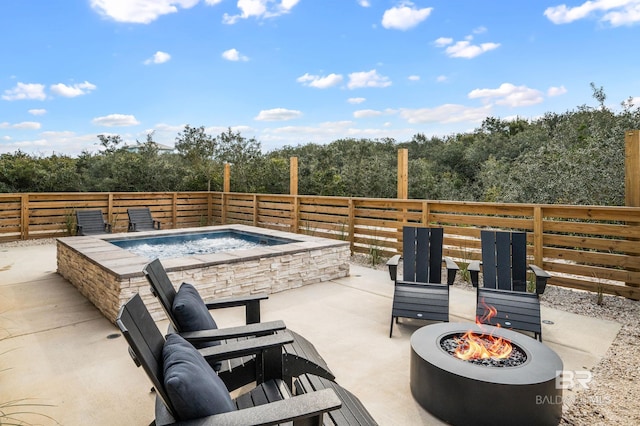 view of patio featuring an outdoor fire pit, an outdoor hot tub, and a view of trees