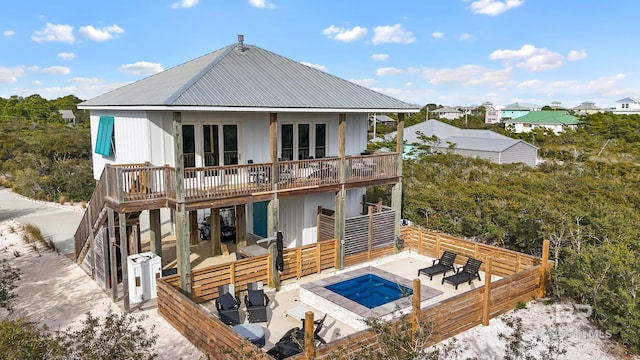 back of house with a hot tub, metal roof, fence, a deck, and a patio area