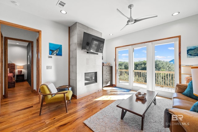 living area featuring light wood-type flooring, visible vents, a fireplace, and recessed lighting