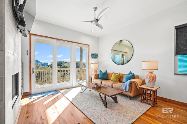 living area with a healthy amount of sunlight, ceiling fan, baseboards, and wood finished floors