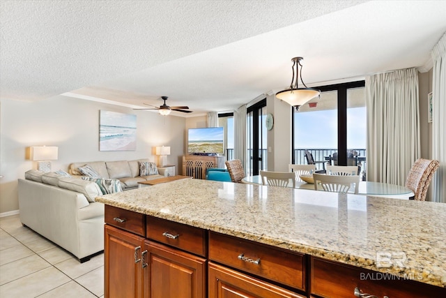 kitchen featuring a textured ceiling, light stone counters, light tile floors, and decorative light fixtures