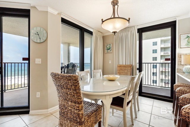 dining area featuring crown molding, a textured ceiling, light tile floors, and a water view