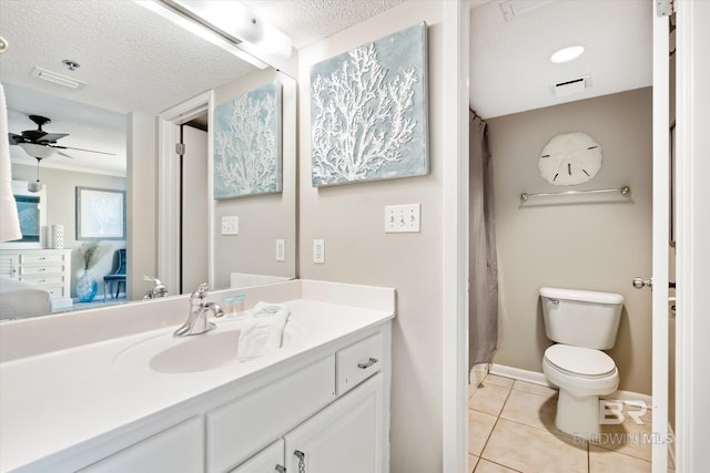 bathroom with ceiling fan, toilet, tile flooring, a textured ceiling, and vanity