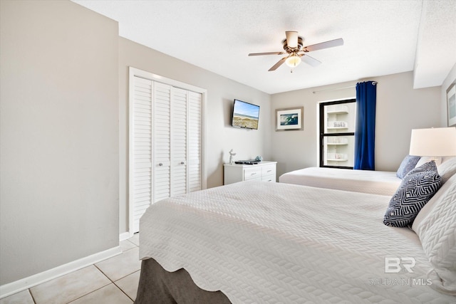 tiled bedroom featuring a closet, ceiling fan, and a textured ceiling