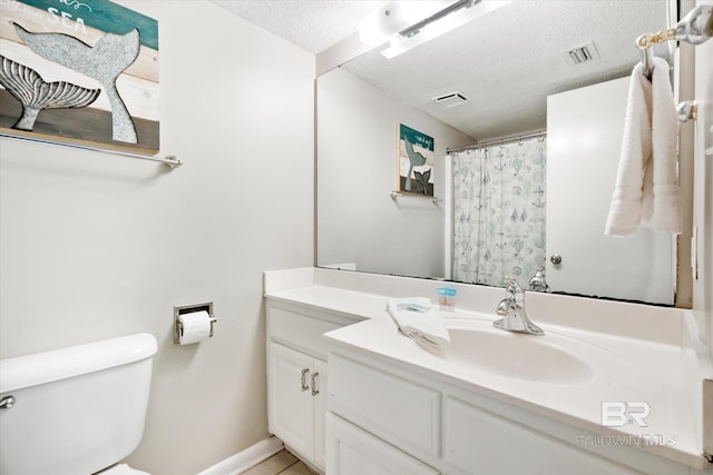 bathroom with a textured ceiling, oversized vanity, and toilet