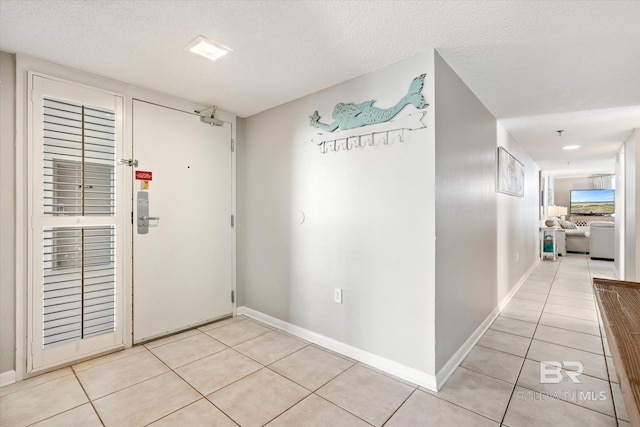 hall featuring a textured ceiling and light tile flooring