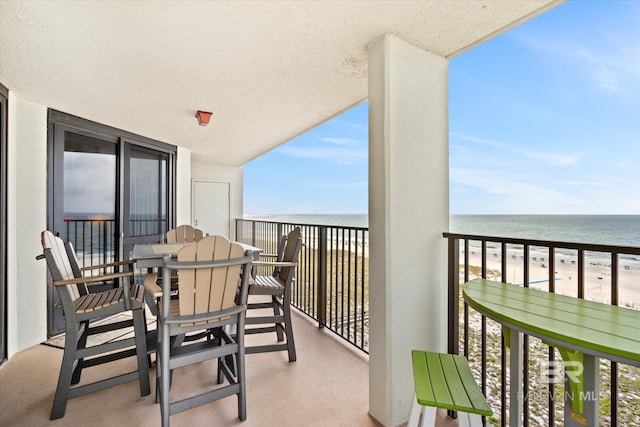 balcony with a water view and a view of the beach