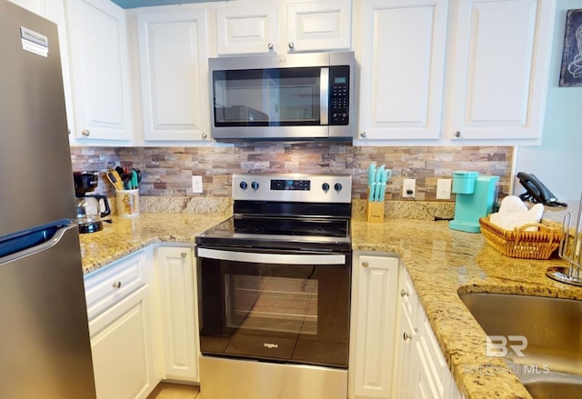 kitchen with white cabinetry, light stone counters, tasteful backsplash, and appliances with stainless steel finishes