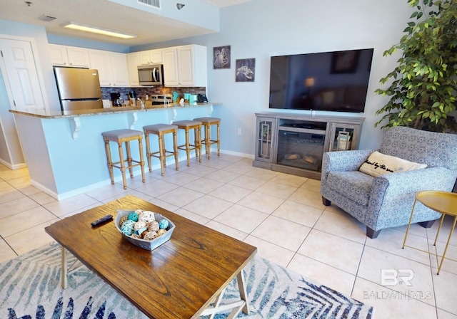 living room featuring light tile patterned floors, baseboards, and visible vents