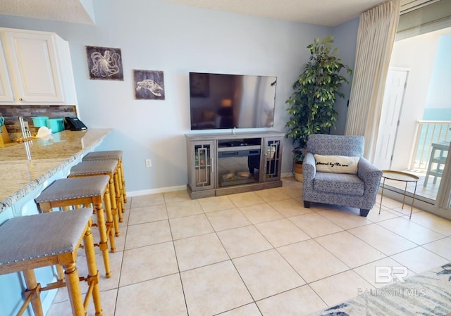 living room with a glass covered fireplace, light tile patterned floors, and baseboards