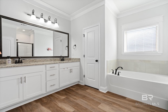 bathroom with hardwood / wood-style flooring, a tub to relax in, ornamental molding, and vanity